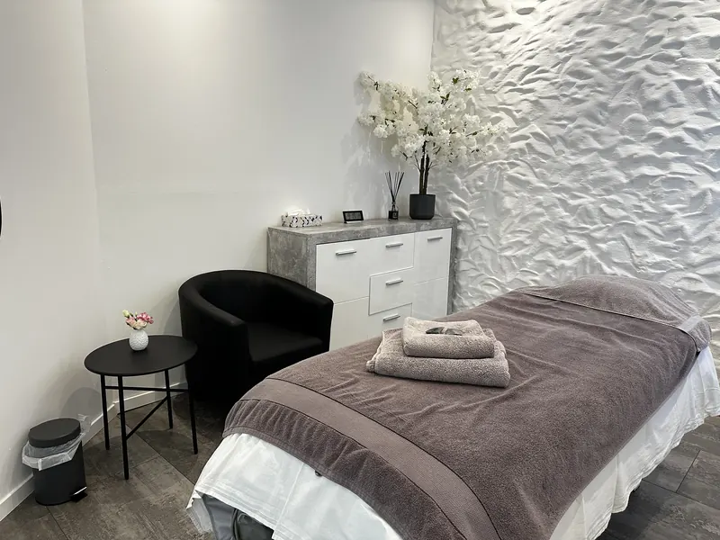 Behandlungsraum mit Massageliege, Sessel und Kirschblütenzweig